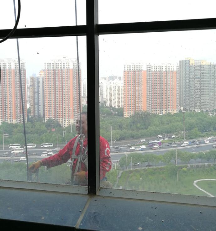 窗外高空中的蜘蛛人一一检查每一块玻璃密封胶